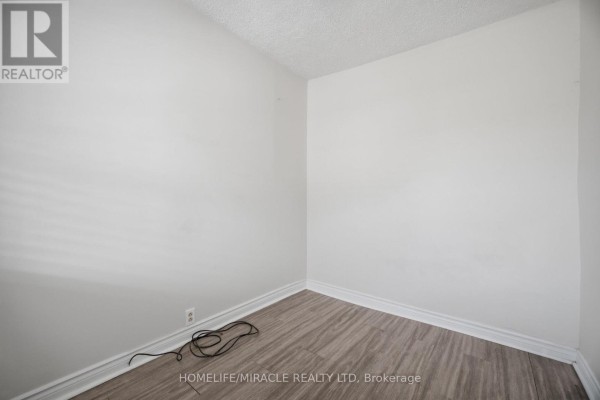 Empty room with wood-look laminate floors and white walls - 25 Hope Avenue Hamilton