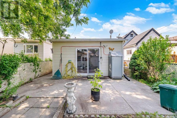 Backyard patio with sliding door, hose, rake, statue & storage unit - 25 Hope Avenue Hamilton