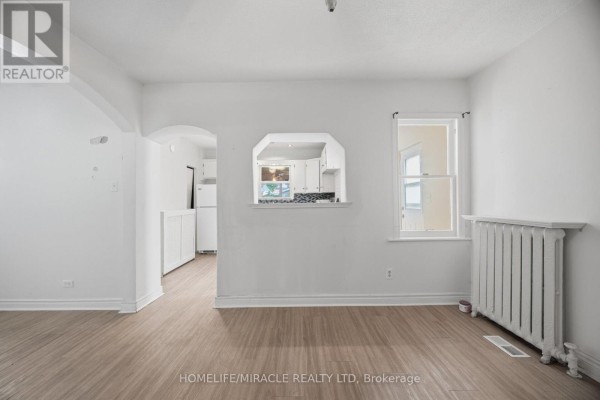 Living room with pass-through window to kitchen, radiator, and wood-look floors - 25 Hope Avenue Hamilton