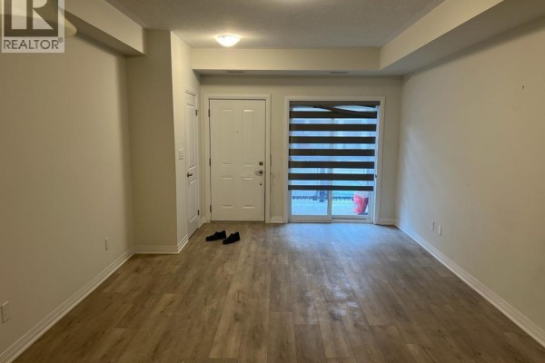 Living area with a white front door, sliding glass doors, and light wood flooring. - 25 Isherwood Avenue Unit# A10, Cambridge