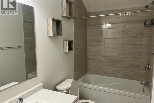 Bathroom with a bathtub, toilet, vanity, and tiled walls. - 25 Isherwood Avenue Unit# A10, Cambridge