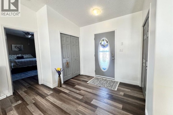View of the kitchen from the other side, showing the breakfast bar, dining table, stainless steel refrigerator, and ample cabinet space. - 25 Keystone Place, Whitecourt