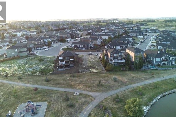 Aerial view of the vacant lot surrounded by houses, a pond, and green space. - 25 Lakes Estates Circle, Strathmore