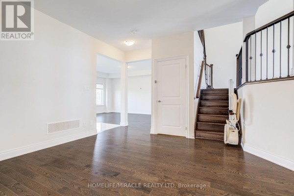 Interior view of a home with dark hardwood floors and a staircase. - 25 Lorne Thomas Place, New Tecumseth