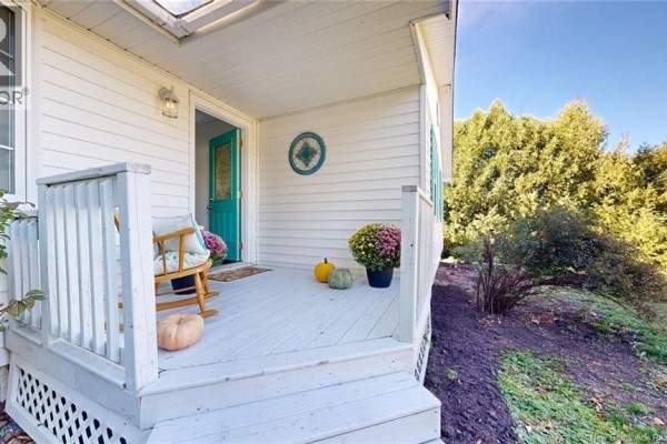 Front porch with light grey decking, white railings, and a turquoise front door. - 25 Mccarron Drive, Quispamsis