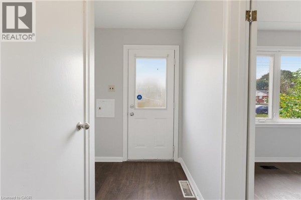 Interior hallway with a white door, white door frame, and dark laminate flooring. - 25 Meinzinger Avenue, Kitchener