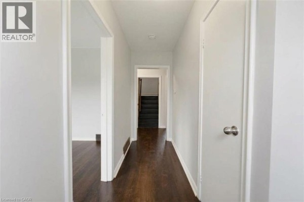 Room with light grey walls, dark laminate flooring, and a large window overlooking the street. - 25 Meinzinger Avenue, Kitchener