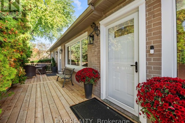 Wooden front porch with seating, bench, potted plants, and the white front door. - 25 Morton Avenue, East Gwillimbury