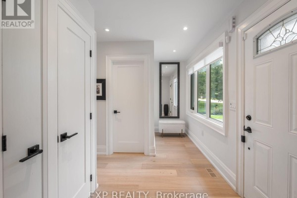 Bright interior hallway with white walls, light wood floors, and black door hardware. - 25 Morton Avenue, East Gwillimbury