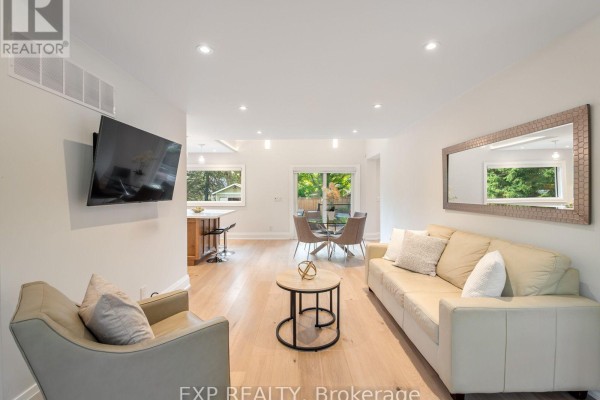 Open concept living and dining area with a sofa, armchair, coffee table, and dining set. - 25 Morton Avenue, East Gwillimbury