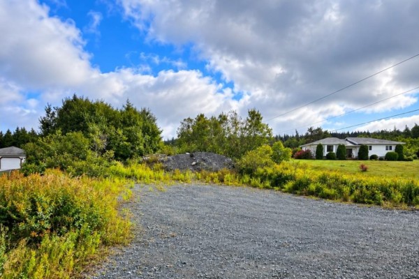 Gravel area with surrounding vegetation, showing a white house on the right. - 25 Newfound Lane, Bay Roberts
