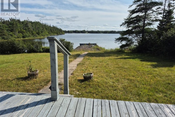 Aerial view of the property featuring two houses, a garage, and a boathouse near a frozen lake and surrounding trees. - 25 Ocean Pond Road, Ocean Pond