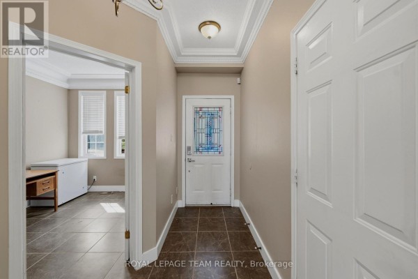 Interior foyer with tiled floors, a white front door with stained glass, and a doorway to a room. - 25 Oldfield Street, Ottawa