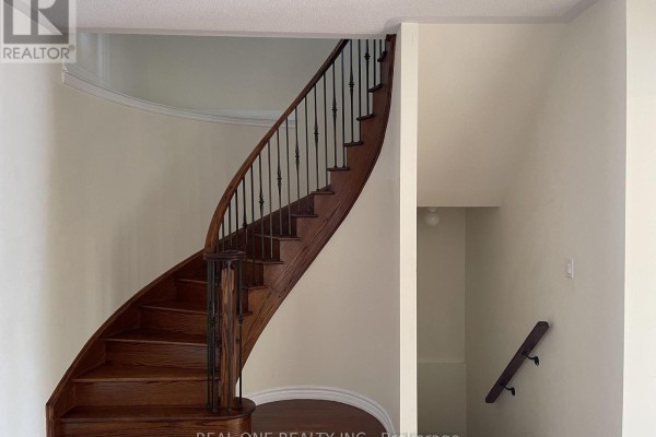 Close-up of a curved wooden staircase with black metal railings. - 25 Paper Mills Crescent, Richmond Hill