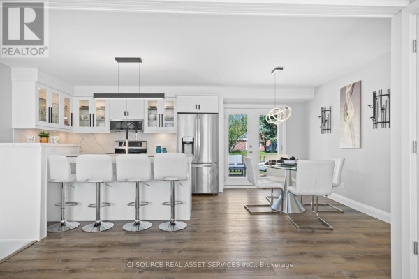 Modern kitchen with white island, stainless steel appliances, and adjacent dining area. - 25 Paulson Court, St  Thomas