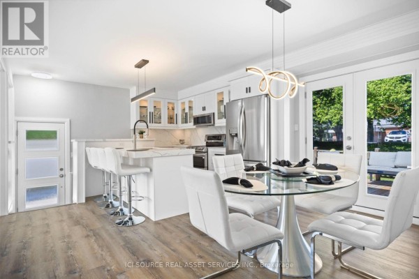 Dining area and kitchen with white chairs, glass table, and french doors to the backyard. - 25 Paulson Court, St  Thomas