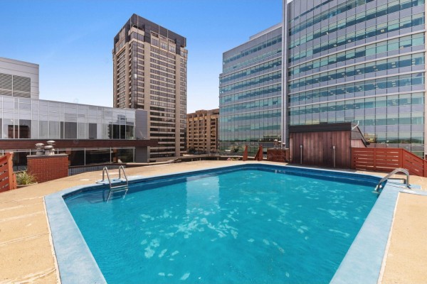 Outdoor swimming pool with blue water on a tiled rooftop terrace. - 25 Rue Victoria, #501, Gatineau