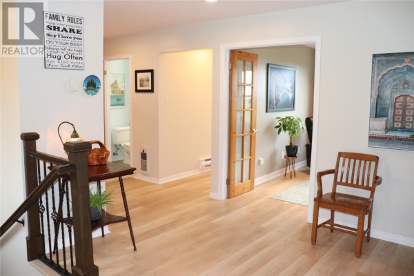 Interior hallway with light wood floors, leading to a bathroom and a living area with glass-paneled doors. - 25 Seaside Drive, Kippens
