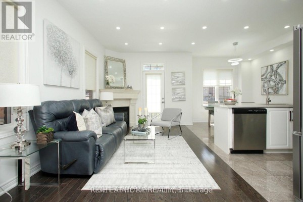 Living room with a dark blue sofa, a fireplace, and a glass coffee table. - 25 Sibella Way, Vaughan