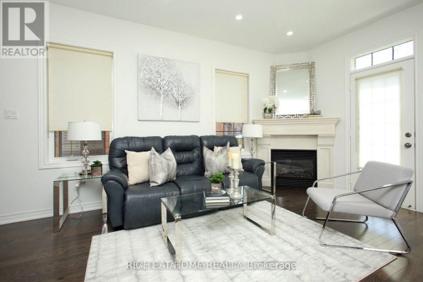 Living room featuring a fireplace, sofa, and a door to the outside. - 25 Sibella Way, Vaughan