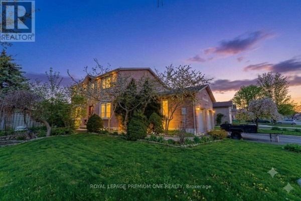 Side view of the brick home with a garage and well-maintained lawn under a colorful sky. - 25 Sir Lancelot Court, Caledon
