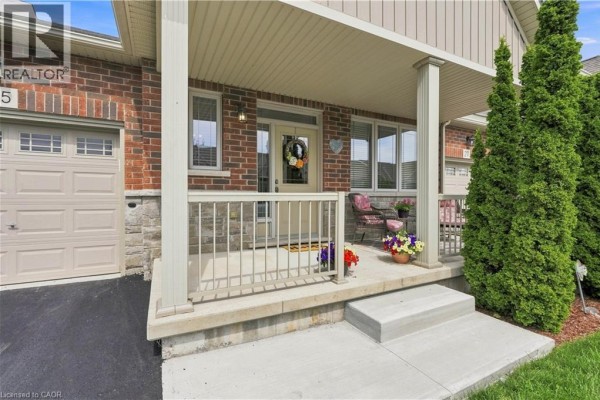 Front porch of a townhouse with a white railing, chairs, and decorative plants. - 25 Stickland Lane, Binbrook