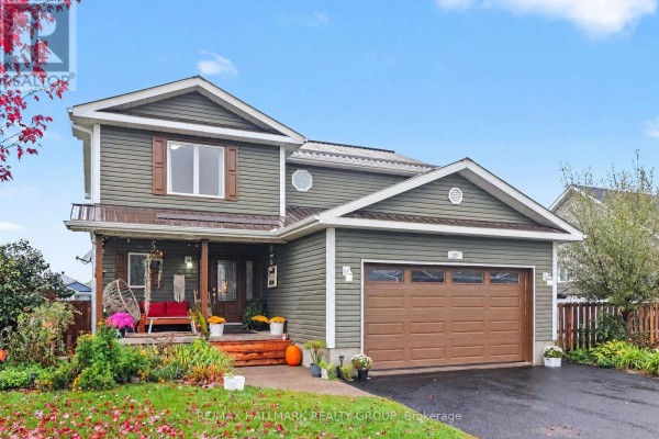 Front exterior of a two-story house with green siding and a brown garage door on a cloudy day. - 25 Tabitha Cres Crescent, North Dundas