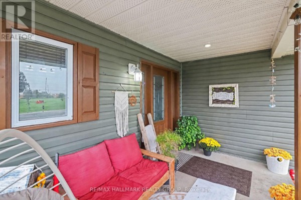 Close-up of the front porch with a sofa, plants, and the entrance to the house. - 25 Tabitha Cres Crescent, North Dundas