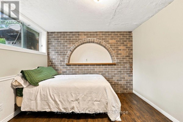 Bedroom with brick accent wall, arched niche, wood shelf, and window - 25 Upcott Crescent London South