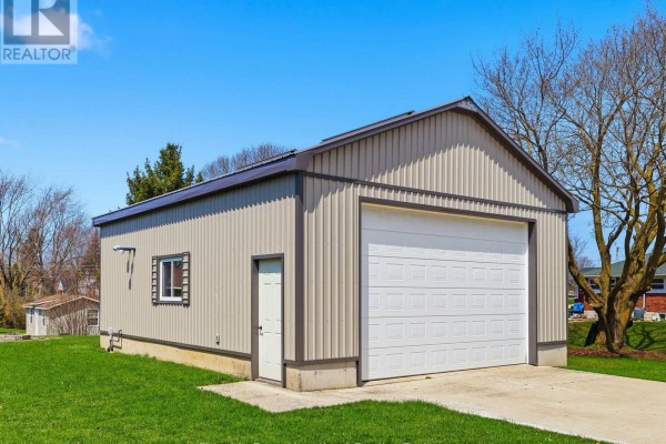 A detached metal garage with a white garage door and a single door. - 25 Vincent Street, South Bruce