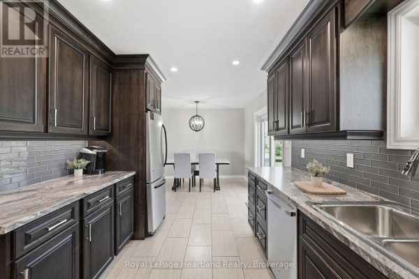 Kitchen with dark wood cabinets, granite counters, subway tile backsplash, and dining area - 25 Vincent Street South Bruce