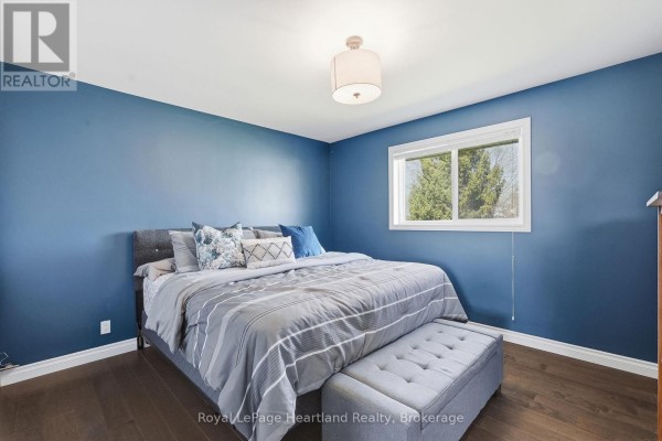 Bedroom with king bed, upholstered bench, blue walls, wood floors - 25 Vincent Street South Bruce