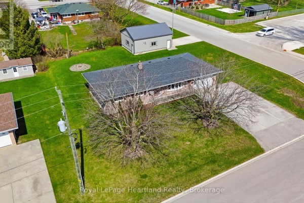 Brick bungalow with attached and detached garages, paved driveway, and mature trees - 25 Vincent Street South Bruce