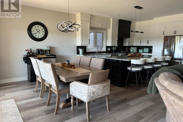 Open concept dining and kitchen area with a large wooden table and island. - 250 Colbeck Drive S, Welland