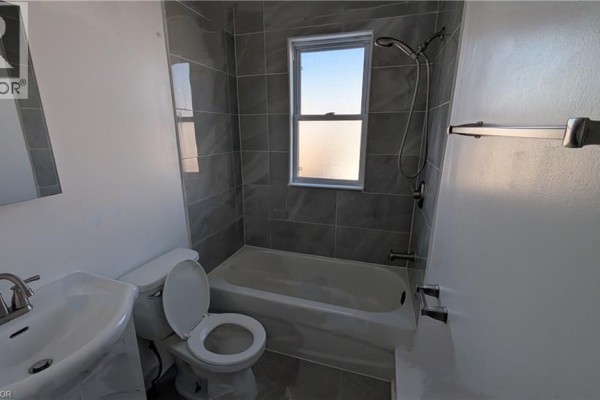 Empty living room space with wooden floors and a large window providing natural light. - 250 Highland Road W Unit# 2 Main Right Side, Stoney Creek