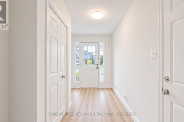 Interior hallway with white walls, laminate flooring, and a view of the front door. - 250 Parkvale Drive, Kitchener