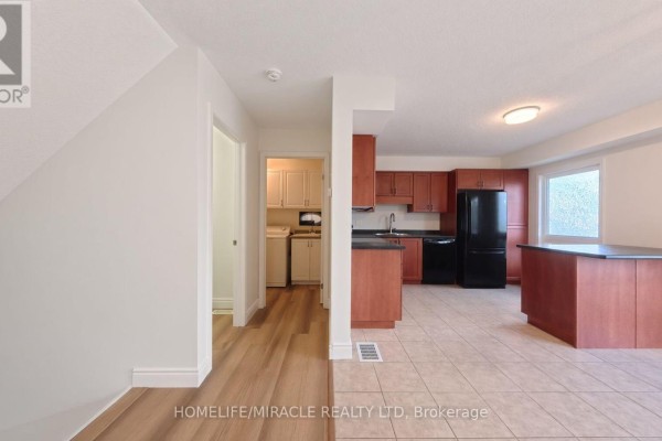 Open concept kitchen with dark appliances, wood cabinets, and island, adjacent to laundry room. - 250 Parkvale Drive, Kitchener