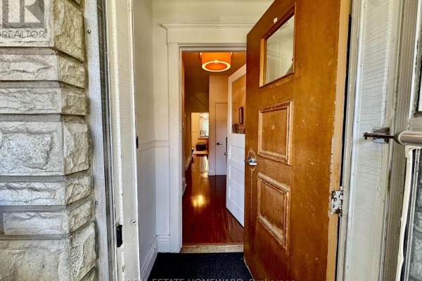 View from the open front door into a hallway with wooden floors and a wooden door. - 250 Rushton Road, Toronto