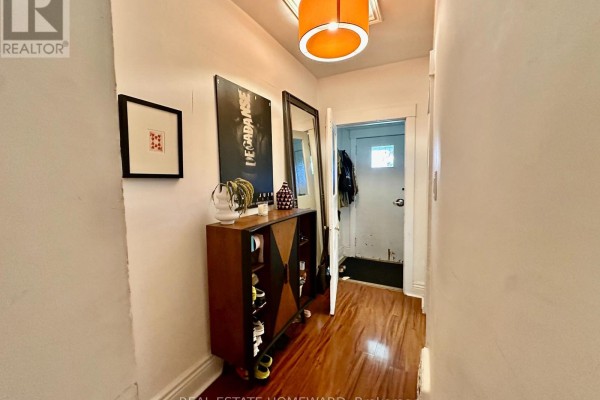 Interior hallway with hardwood floors, a shoe cabinet, and artwork on the walls. - 250 Rushton Road, Toronto