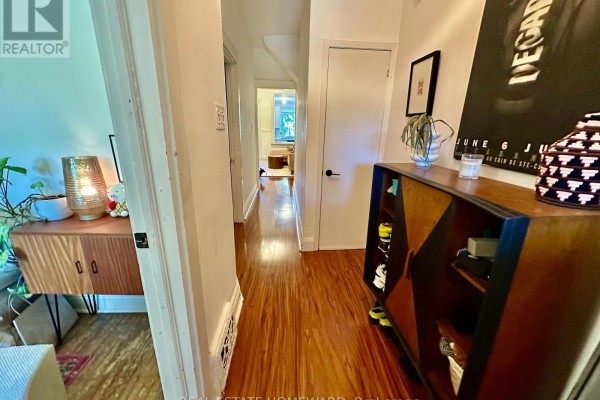 View down a hallway with wooden floors, a cabinet, and doors leading to other rooms. - 250 Rushton Road, Toronto
