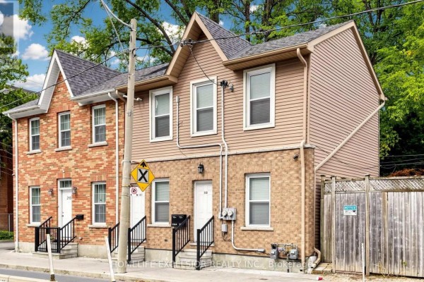 Exterior view of multi-family homes with brick and beige siding, featuring front doors and utilities. - 250 Shuter Street, Toronto