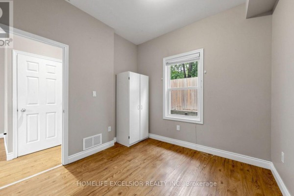 Interior living space with grey walls, wood floors, a counter island, and a white door. - 250 Shuter Street, Toronto