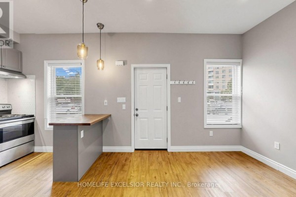 Kitchen area with grey cabinets, stainless steel appliances, a counter island, and wood floors. - 250 Shuter Street, Toronto