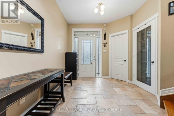 Foyer with glass-paneled front door, tiled floor, and dark mirror. - 250 Tofino Private, Ottawa