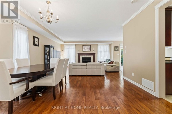 Dining area with dark wood table and white chairs, open to living room. - 250 Tofino Private, Ottawa