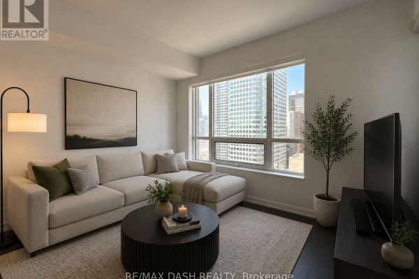 Living room with sectional sofa, coffee table, and large window with city view. - 2501 - 88 Scott Street, Toronto
