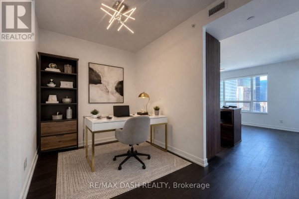 Home office with desk, chair, bookshelf, and city view through opening. - 2501 - 88 Scott Street, Toronto
