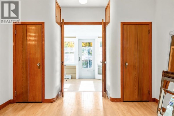 Interior view looking down a hallway towards a sunroom with large windows and glass doors. - 2501 20 Street, Nanton