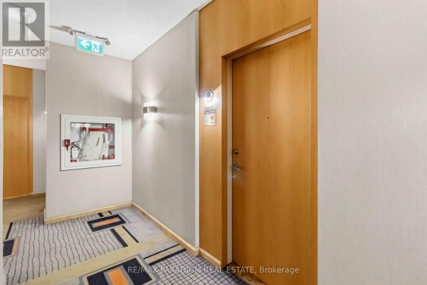 Apartment building hallway with wood-paneled doors and patterned carpet. - 2503 - 3939 Duke Of York Boulevard, Mississauga