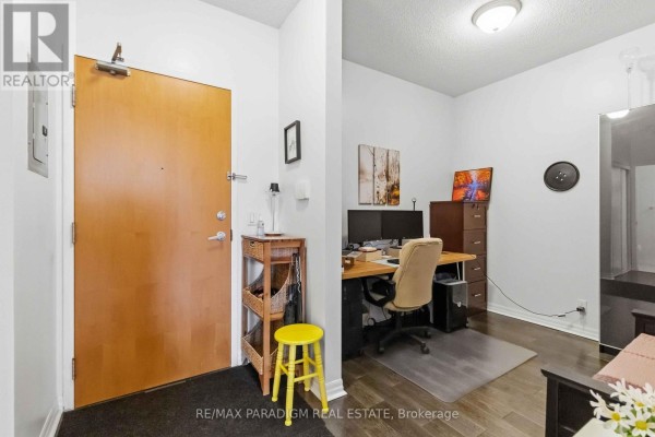 Apartment entryway with a wooden door and a small desk area. - 2503 - 3939 Duke Of York Boulevard, Mississauga